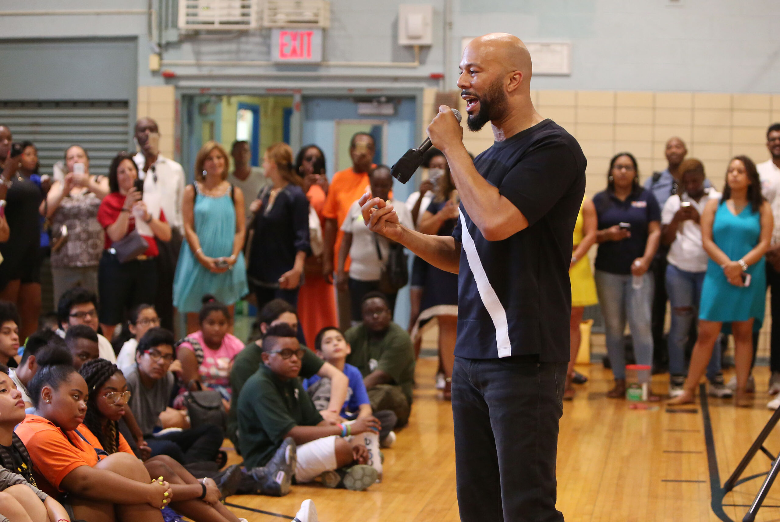 Common speaking to teachers and students in a gymnasium.
